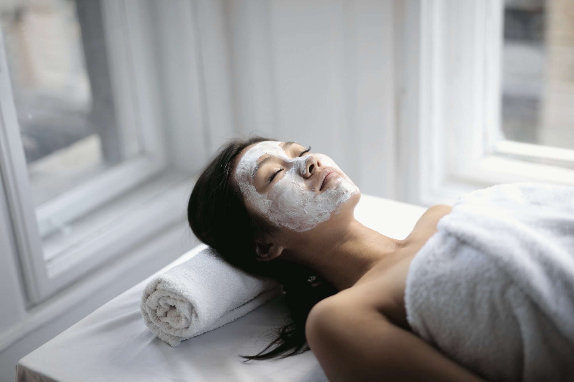 A guest resting by the window after a dermaplaning facial, skin bright and calm.